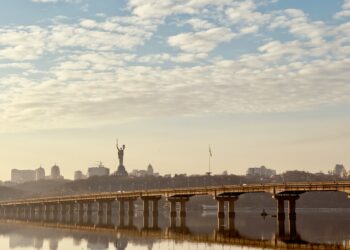 a bridge over a body of water with a statue in the background
