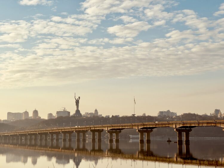 a bridge over a body of water with a statue in the background