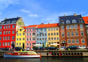 Colorful buildings line a canal with boats and cars.