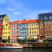 Colorful buildings line a canal with boats and cars.