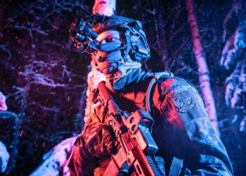 A man with a gun standing in the woods