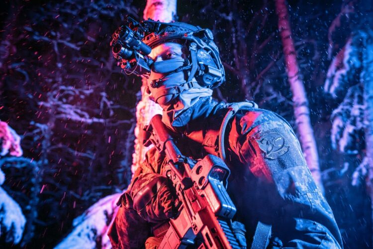 A man with a gun standing in the woods