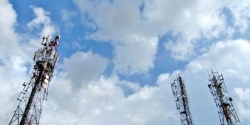 a group of cell towers sitting under a cloudy blue sky