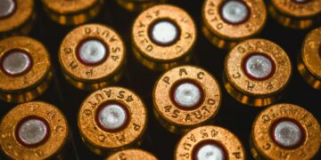 A close-up view of brass 45 auto cartridge casings arranged in a grid