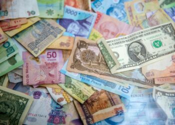 A collection of various international banknotes scattered across a flat surface