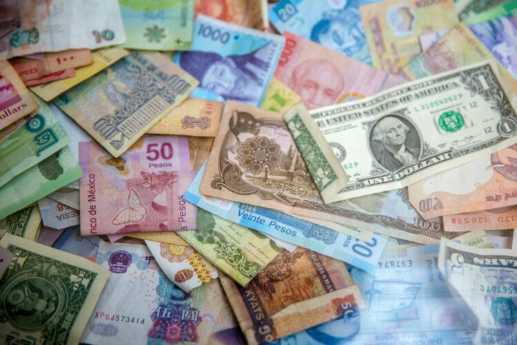 A collection of various international banknotes scattered across a flat surface