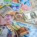 A collection of various international banknotes scattered across a flat surface
