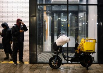 A man standing next to a motorcycle in front of a building